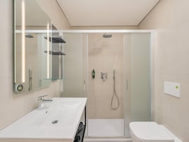 Un bagno moderno con cabina doccia in vetro, un lavandino bianco e un water.