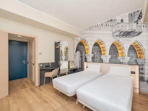 Habitación de hotel con dos camas, un escritorio, una silla y un mural de arcos.