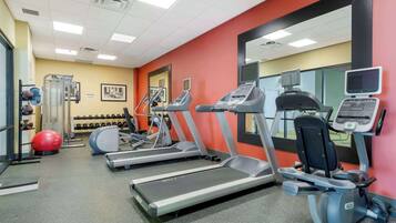 A gym with treadmills, elliptical machines, and exercise balls.