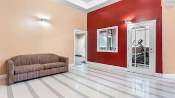 A hallway with a striped sofa, a red wall, and a door with a bike rack.