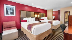 A hotel room with two beds, a desk, and a chair.