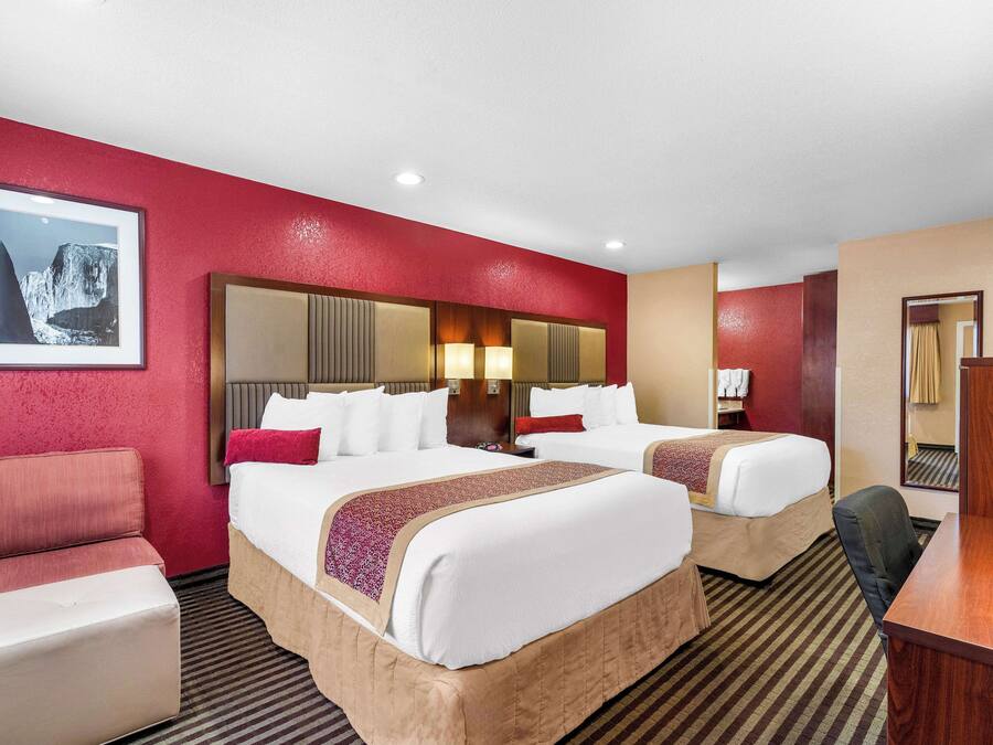Une chambre d’hôtel avec deux lits, un bureau et une chaise.