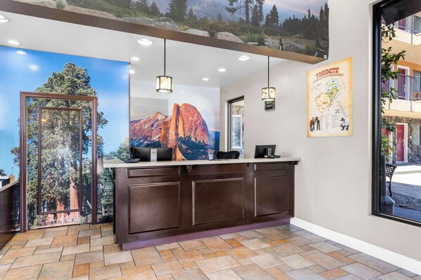 A reception area with a wooden reception desk, a large poster of a mountain, and a map of Yosemite on the wall. - Best Western Plus Yosemite Way Station Motel (Mariposa)