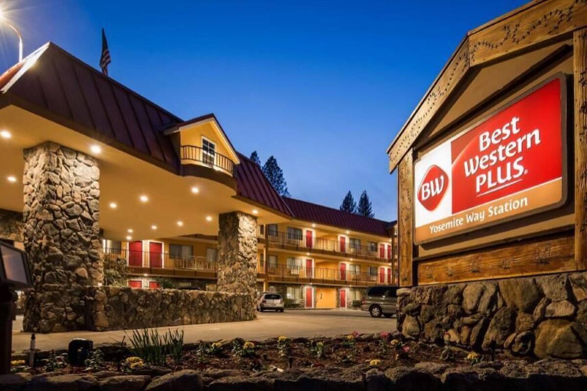 A hotel with a stone facade, multiple balconies, and a sign reading 'Best Western Plus Yosemite Way Station.'