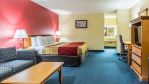 Una habitación de hotel con cama, sofá, escritorio y televisor.