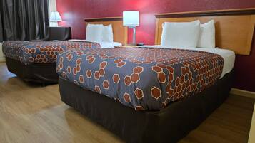 Habitación de hotel con dos camas, una pared roja y suelo de madera.