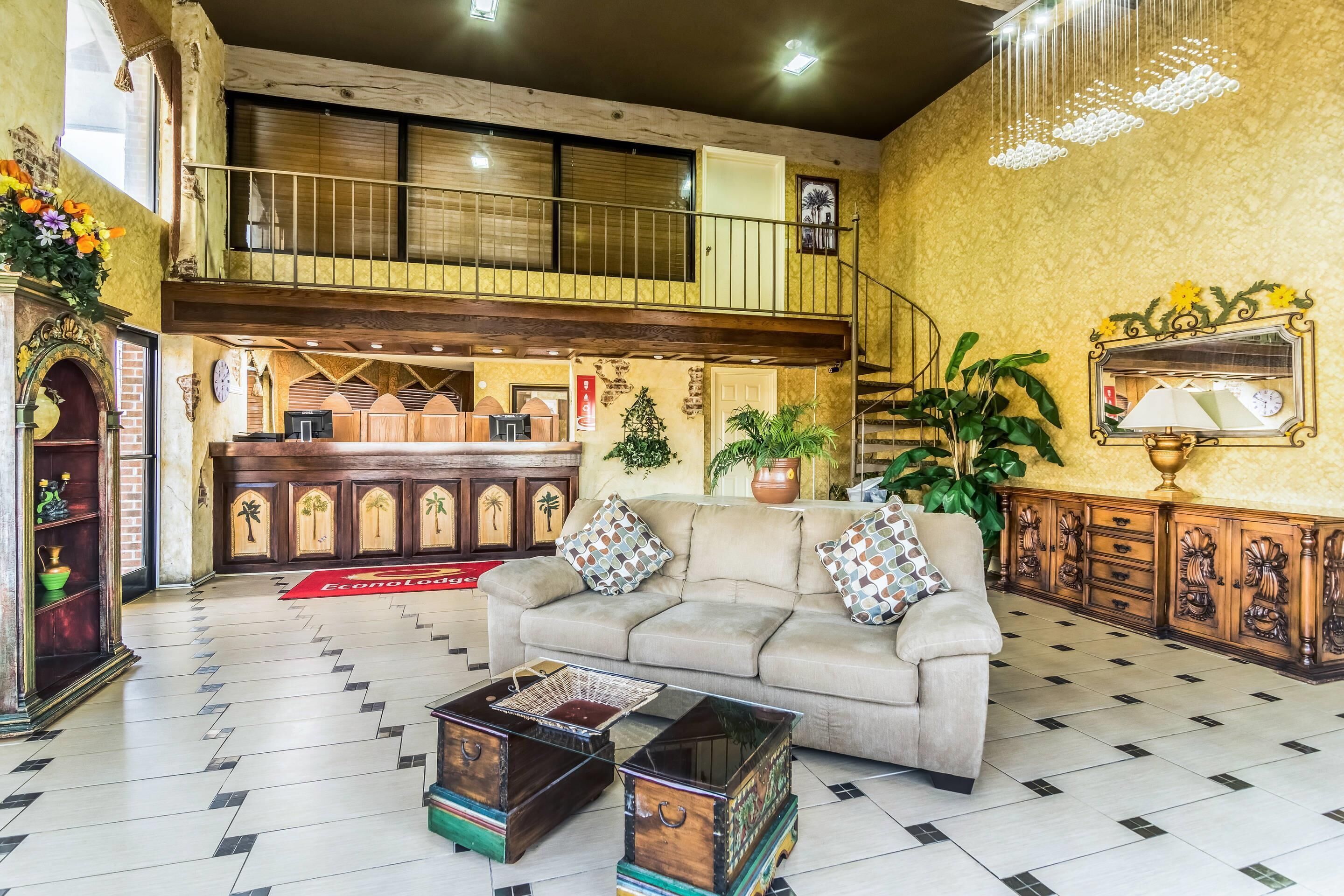 A spacious lobby with a high ceiling, a reception desk, a sofa, and a coffee table.