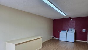 A laundry room with a white washing machine and dryer, a beige countertop, and wooden flooring. - Econo Lodge Whiteville (Whiteville)