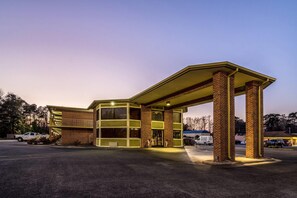 Un motel avec une station-service attenante, caractérisé par une façade en briques et un espace de stationnement couvert.