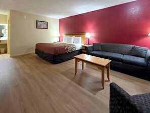 Habitación de hotel con cama, sofá, una mesita y una mesita de noche con lámparas.