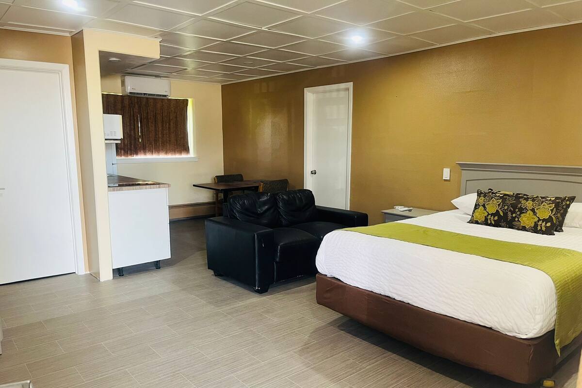 Una habitación de hotel con cama, escritorio, silla y armario.