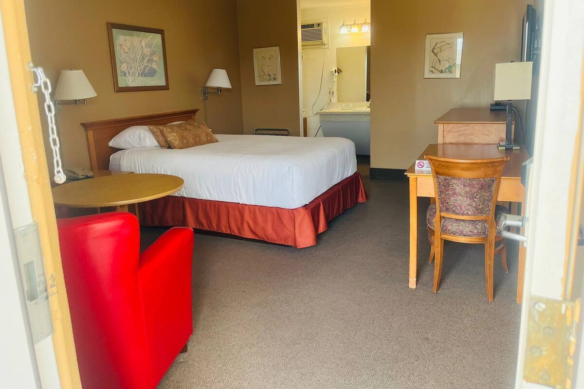 Una habitación de hotel con una cama, un escritorio, una silla y una mesita.