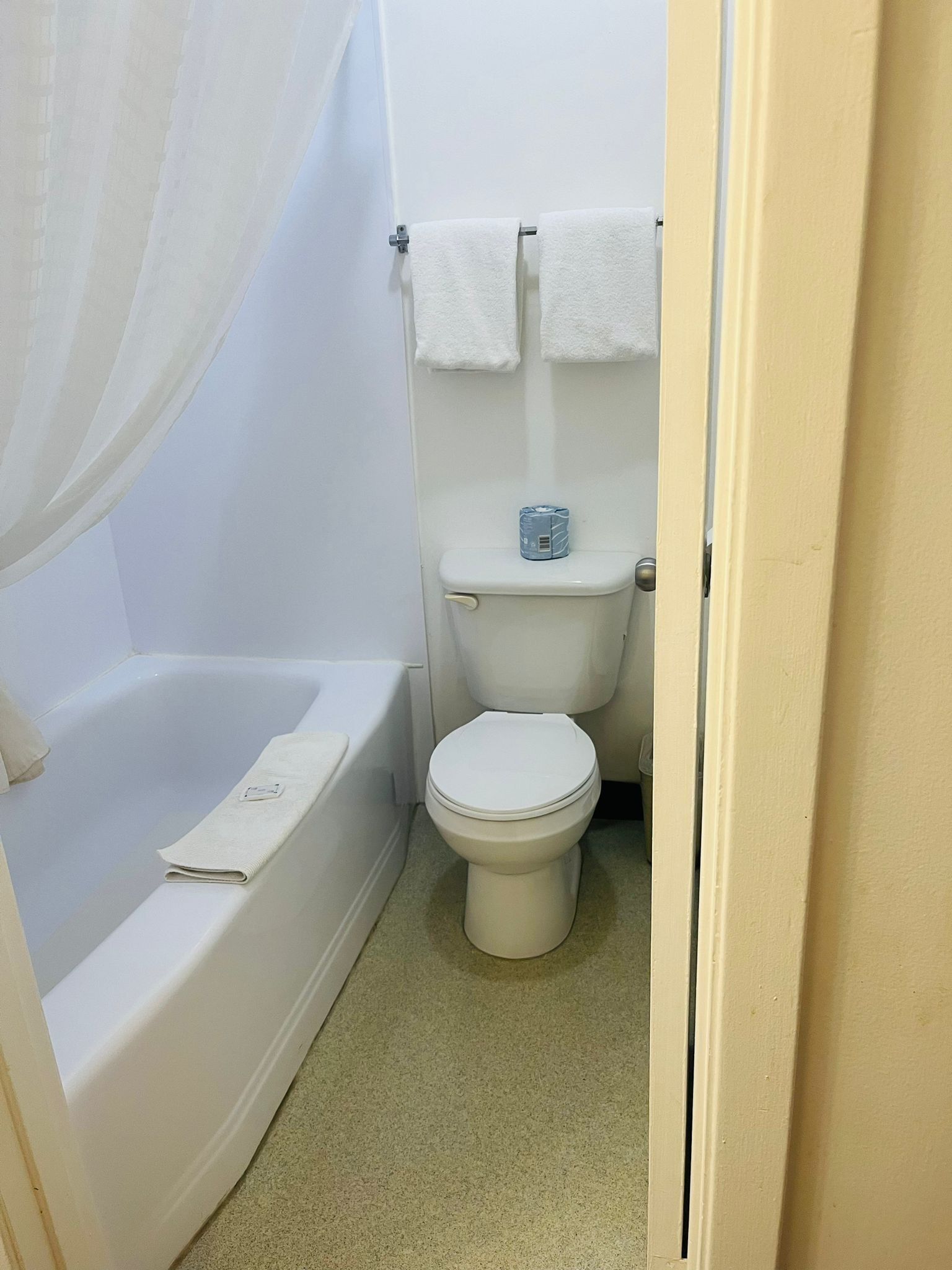 A small, clean bathroom with a toilet, a bathtub, and a shower curtain.