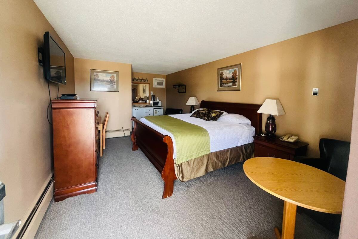 Habitación de hotel con cama, escritorio, silla y una mesita.