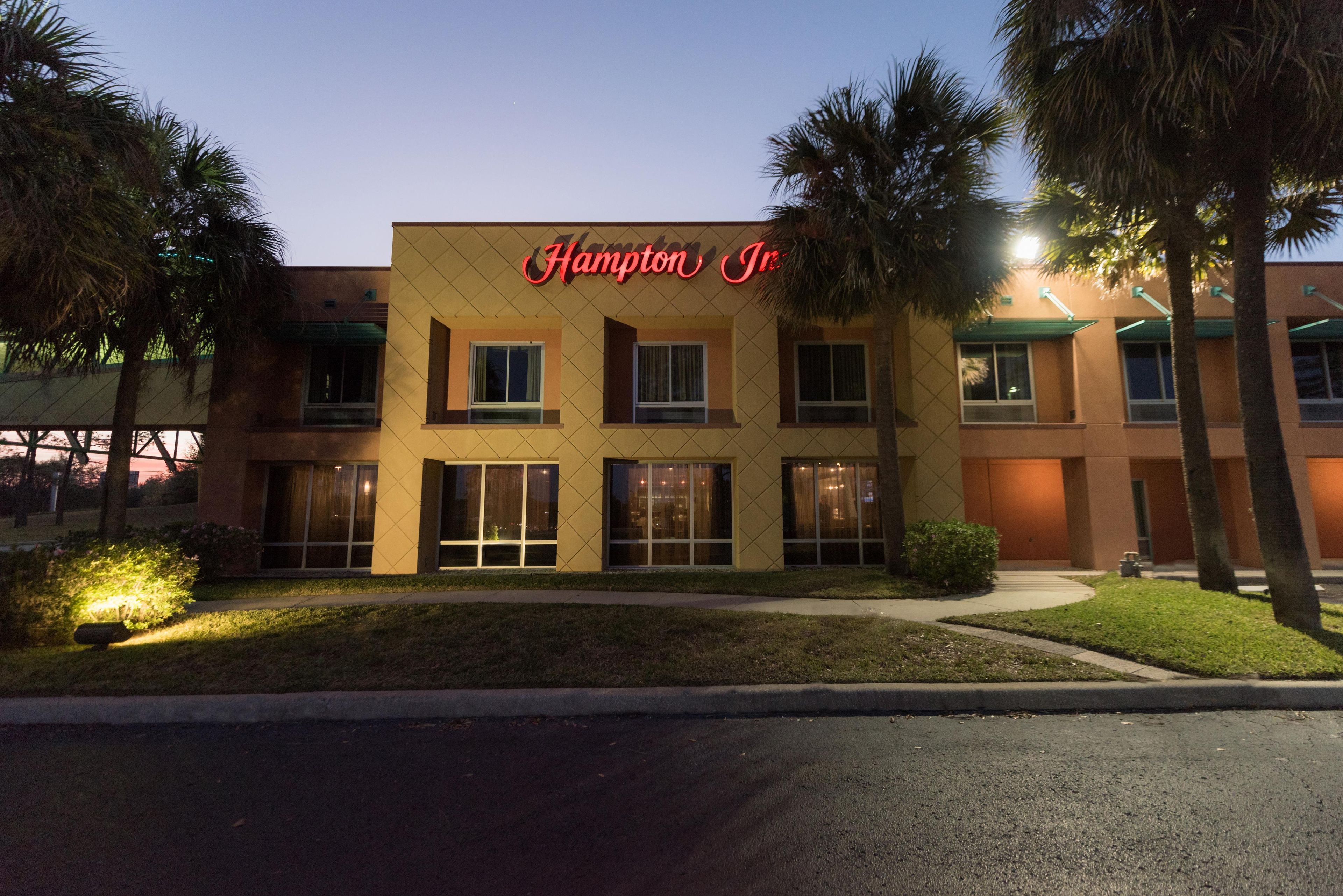 A hotel with a sign reading 'Hampton Inn' and a well-maintained lawn in front.