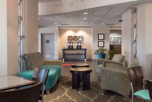 A lobby with seating areas, a coffee station, and framed artwork on the walls.