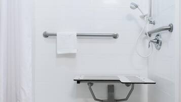 A shower area with a grab bar, a handheld showerhead, and a handheld faucet.