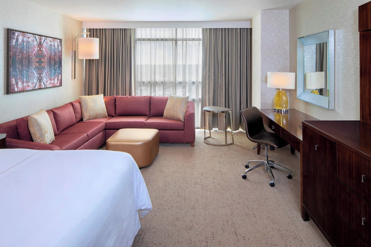 Une chambre d’hôtel avec un grand lit, un canapé, un bureau et une chaise.