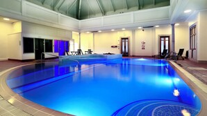 An indoor swimming pool with clear lanes, a changing room area, and a staircase leading to an upper level. - Macdonald Botley Park Hotel & Spa (Southampton)
