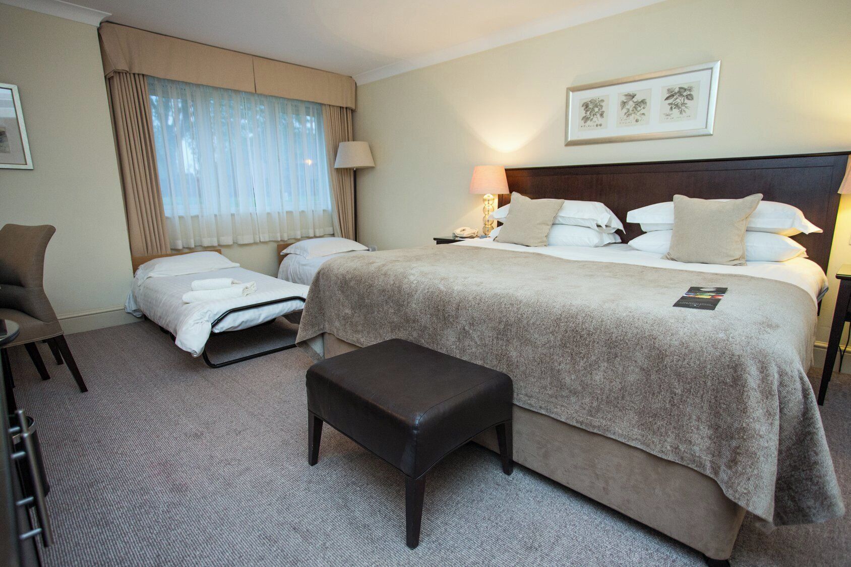 A hotel room with a large bed, two bedside tables, a chair, and a desk.