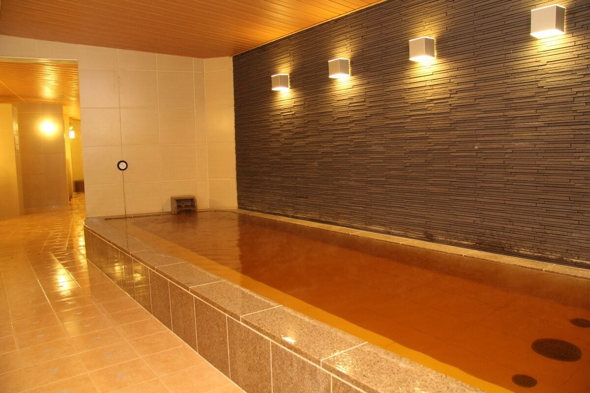 A modern indoor pool area with a tiled floor and a wooden wall with embedded lighting.