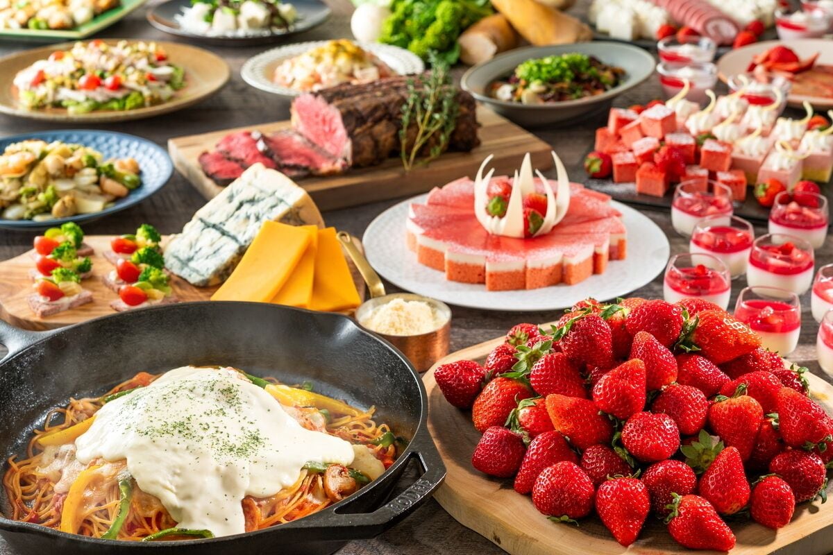 A variety of dishes including pasta, steak, and a large selection of strawberries.