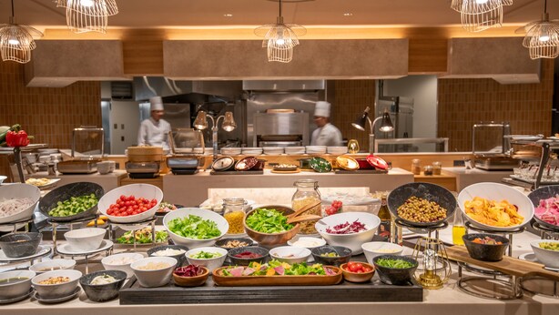 Un bufé con diferentes opciones de comida y un chef al fondo.