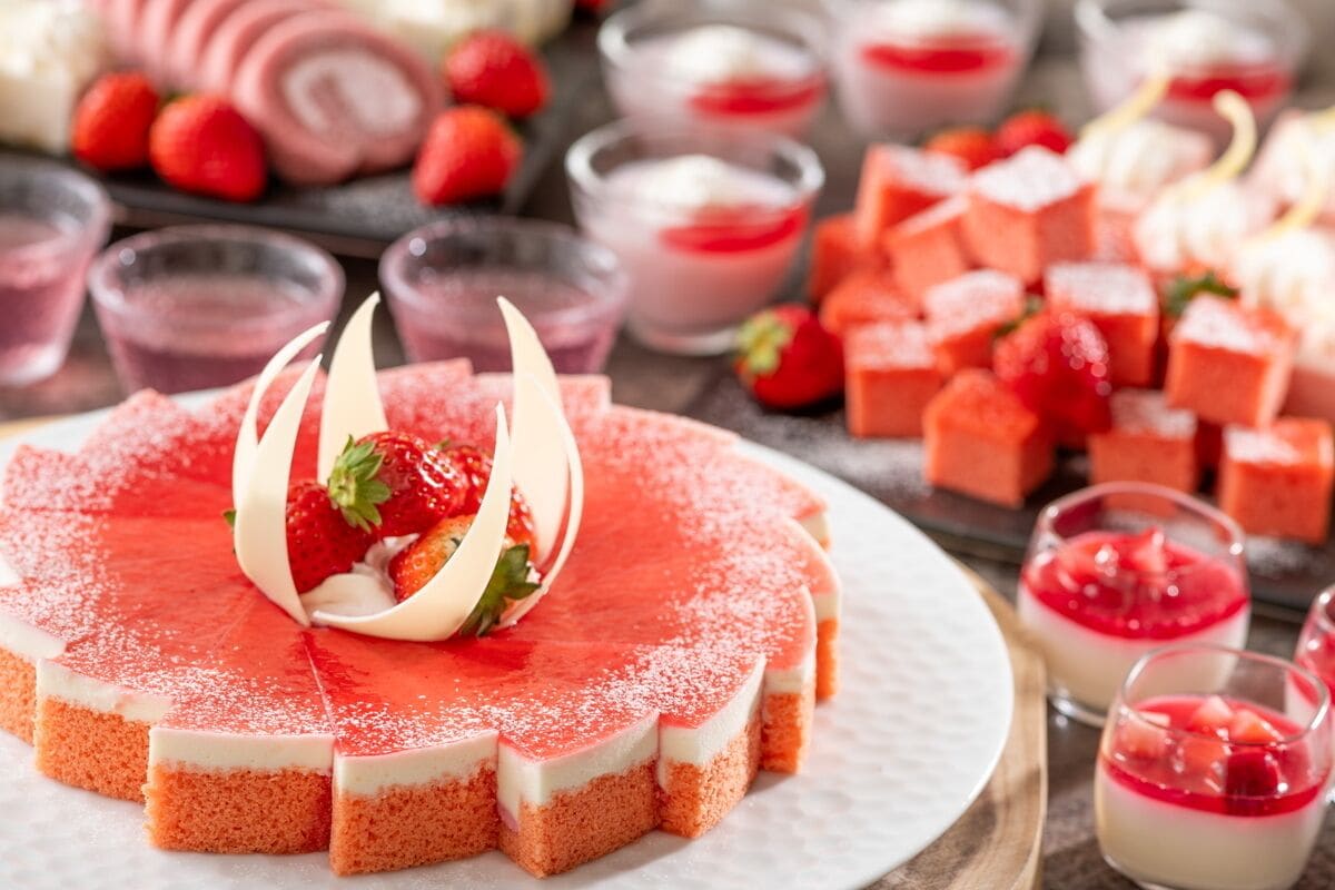 A dessert platter with a cake, strawberries, and various small desserts.