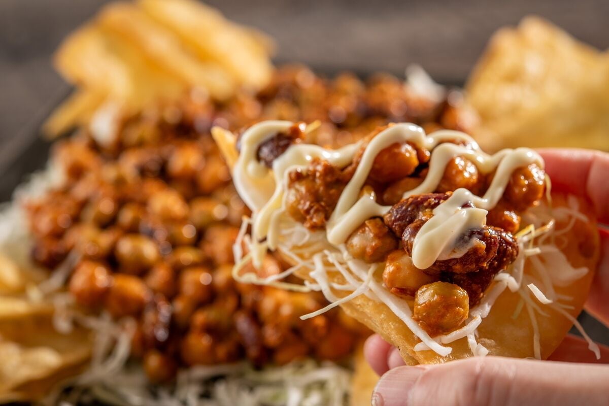 A close-up of a food item with cheese, nuts, and sauce.