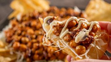 A close-up of a food item with cheese, nuts, and sauce.