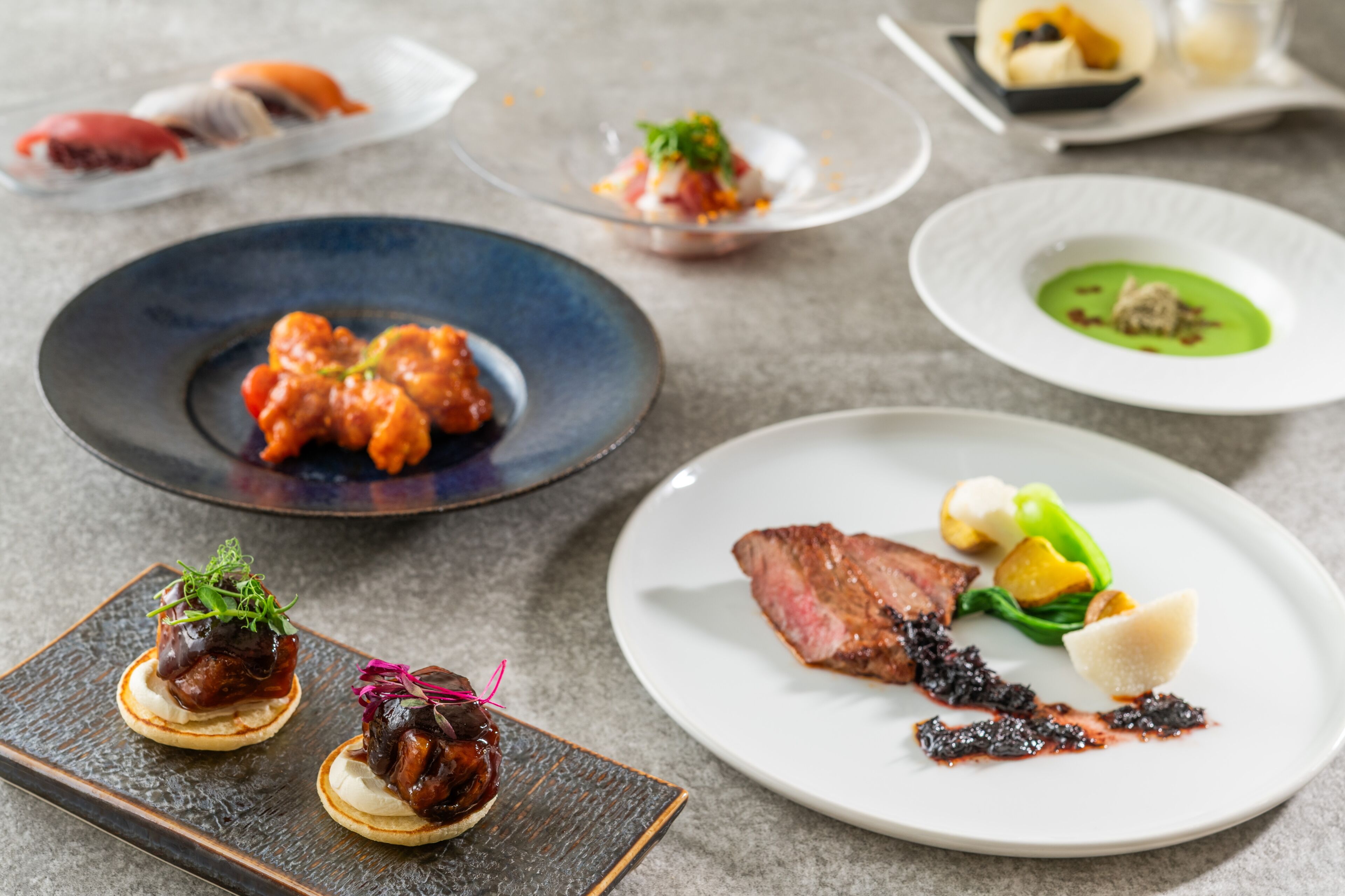 Een verscheidenheid aan gepresenteerde gerechten, waaronder een steak, zeevruchten en groenten, op een tafel gerangschikt.