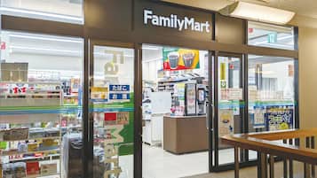 Un magasin FamilyMart avec une entrée bien visible, un distributeur automatique et divers produits exposés sur des étagères.