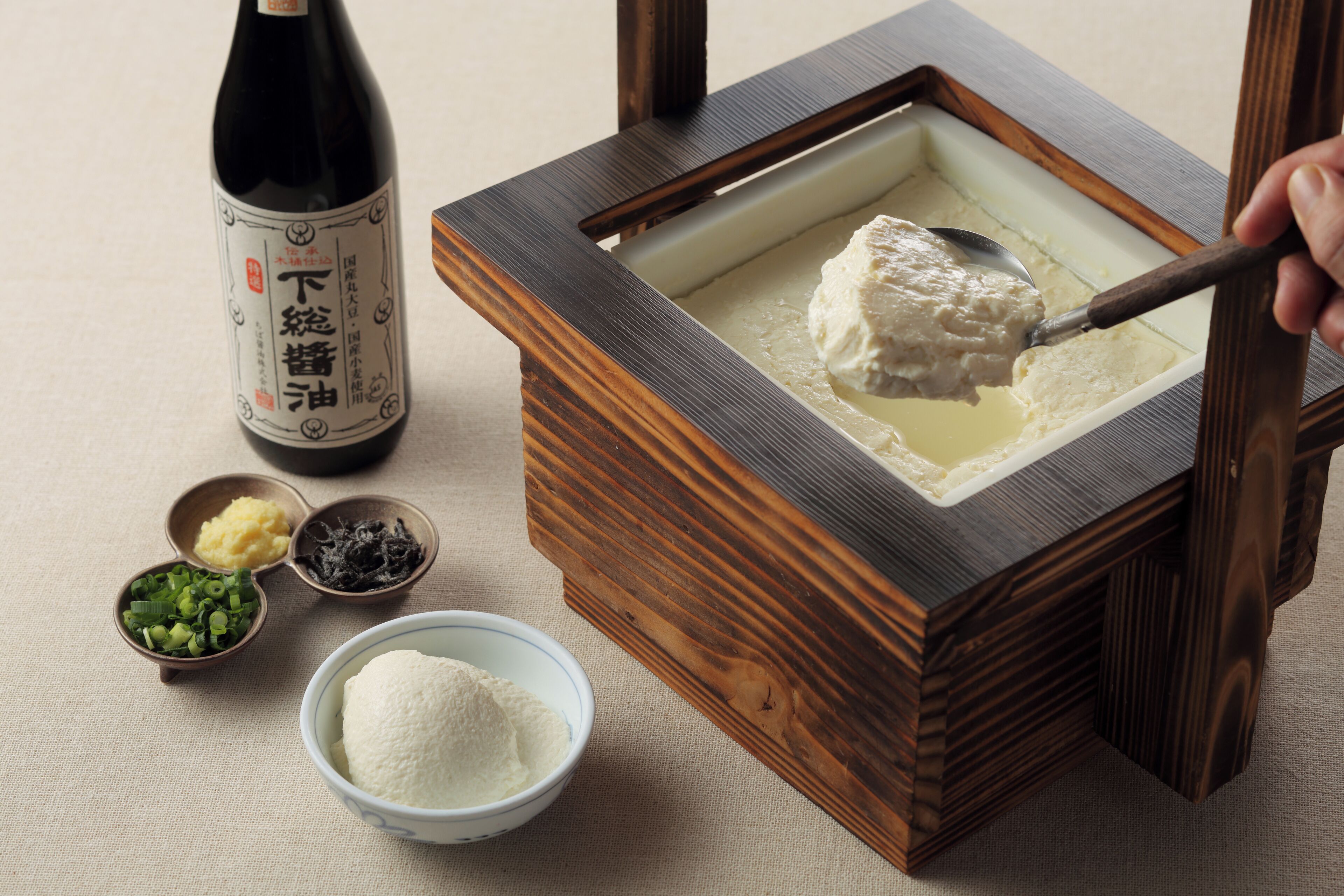 Una botella tradicional de sake japonés, un cofre de madera para sake y diversos condimentos.