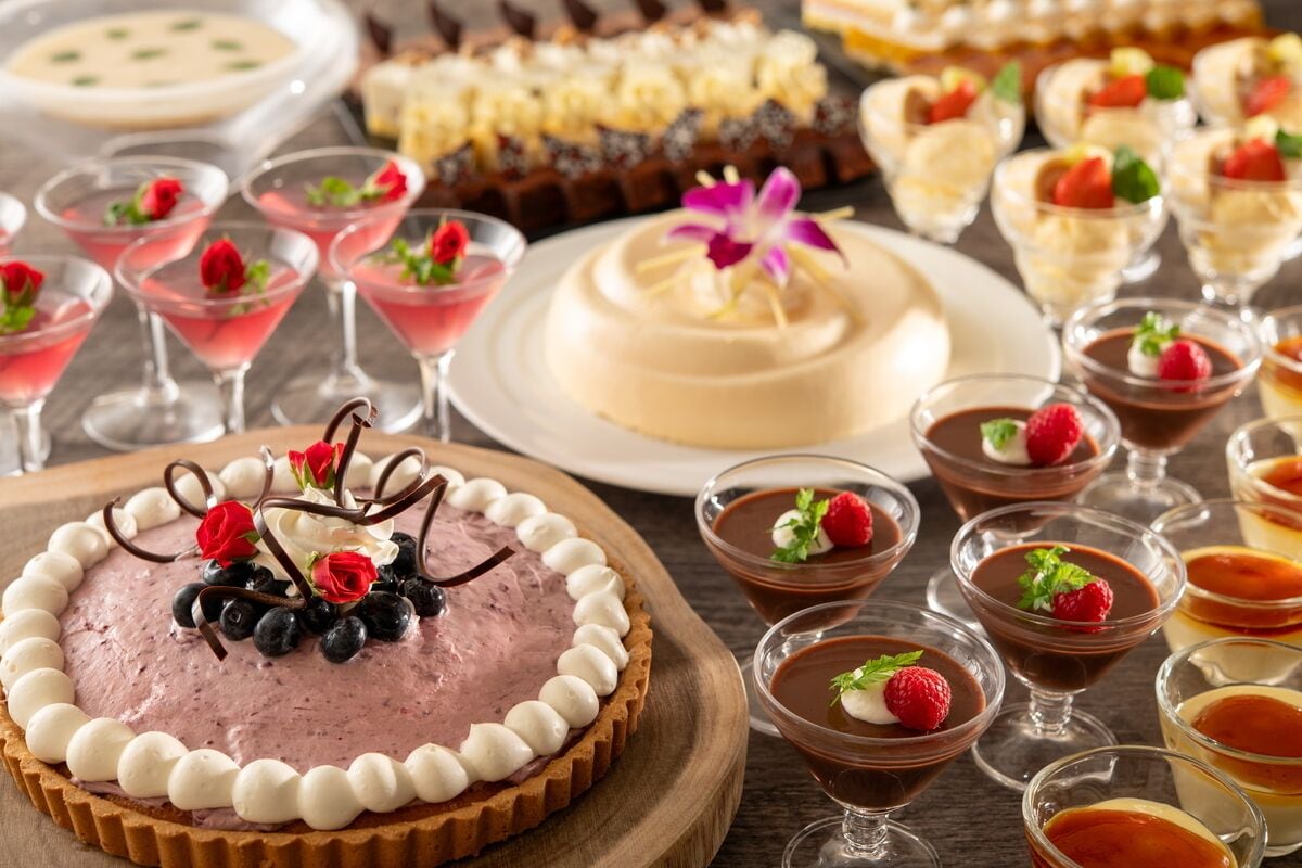 Una variedad de postres, incluyendo una tarta, mini pasteles y dulces de chocolate, dispuestas sobre una tabla de madera.