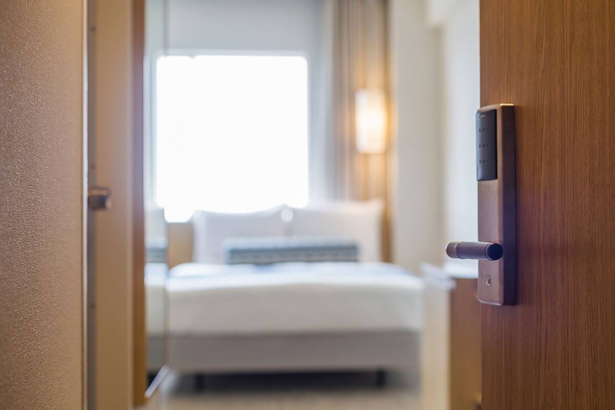 A hotel room entrance with a wooden door and a modern digital lock.