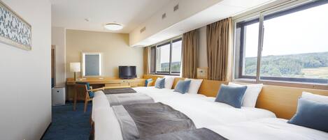 A hotel room with a large bed, a desk, a television, and a window with a view of the outdoors.