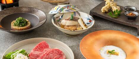 A variety of dishes including raw meat, vegetables, and a bowl of soup.