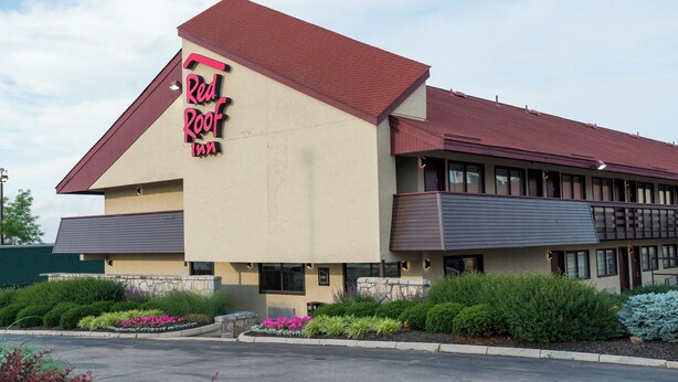 Un Red Roof Inn con un techo rojo característico y paredes exteriores color beige.