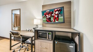 Habitación de hotel con escritorio, microondas, refrigerador, silla, televisor y espejo.