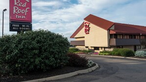 Un Red Roof Inn con cielo despejado, un letrero que indica WiFi gratuito y un jardín bien cuidado.