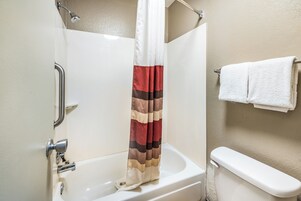 Un baño con bañera, cortina de ducha y barra para toallas.
