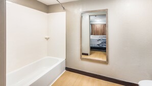 Un baño con bañera, espejo y retrete.