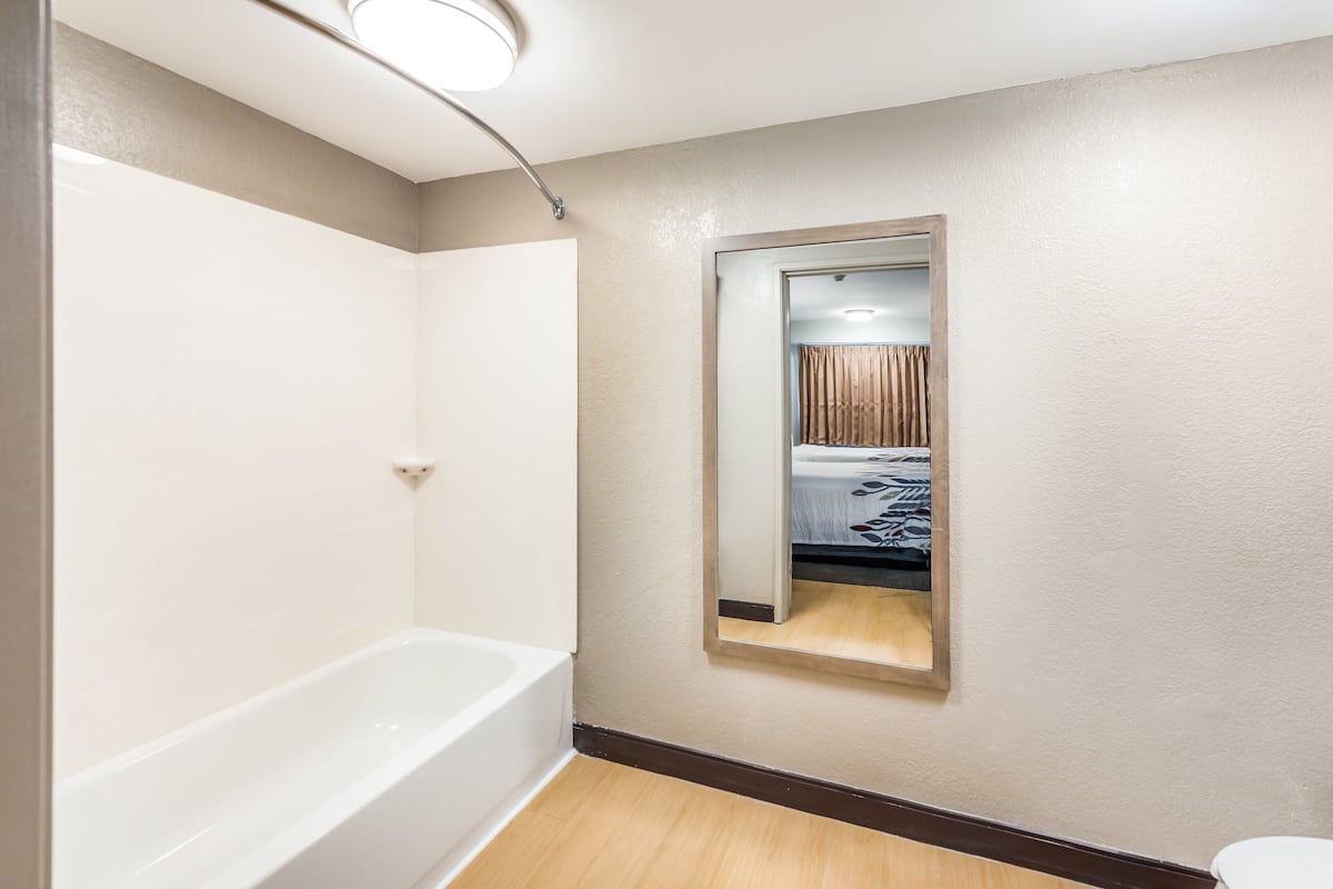 A bathroom with a bathtub, a mirror, and a toilet.