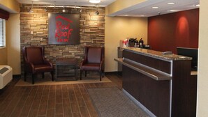 Un vestíbulo de hotel con pared de piedra, un mostrador de recepción, dos sillones de cuero y una mesita.