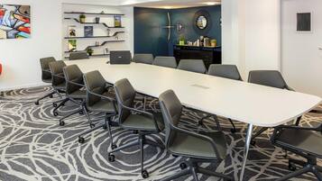 A conference room with a long table, multiple chairs, a laptop, and decorative shelves.