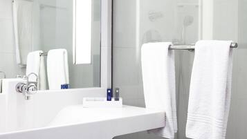 A modern bathroom with a white sink, a mirror, and two white towels hanging on a towel rack.