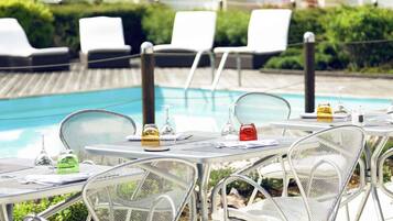 Een buitenzwembad, parasols bij het zwembad en ligstoelen