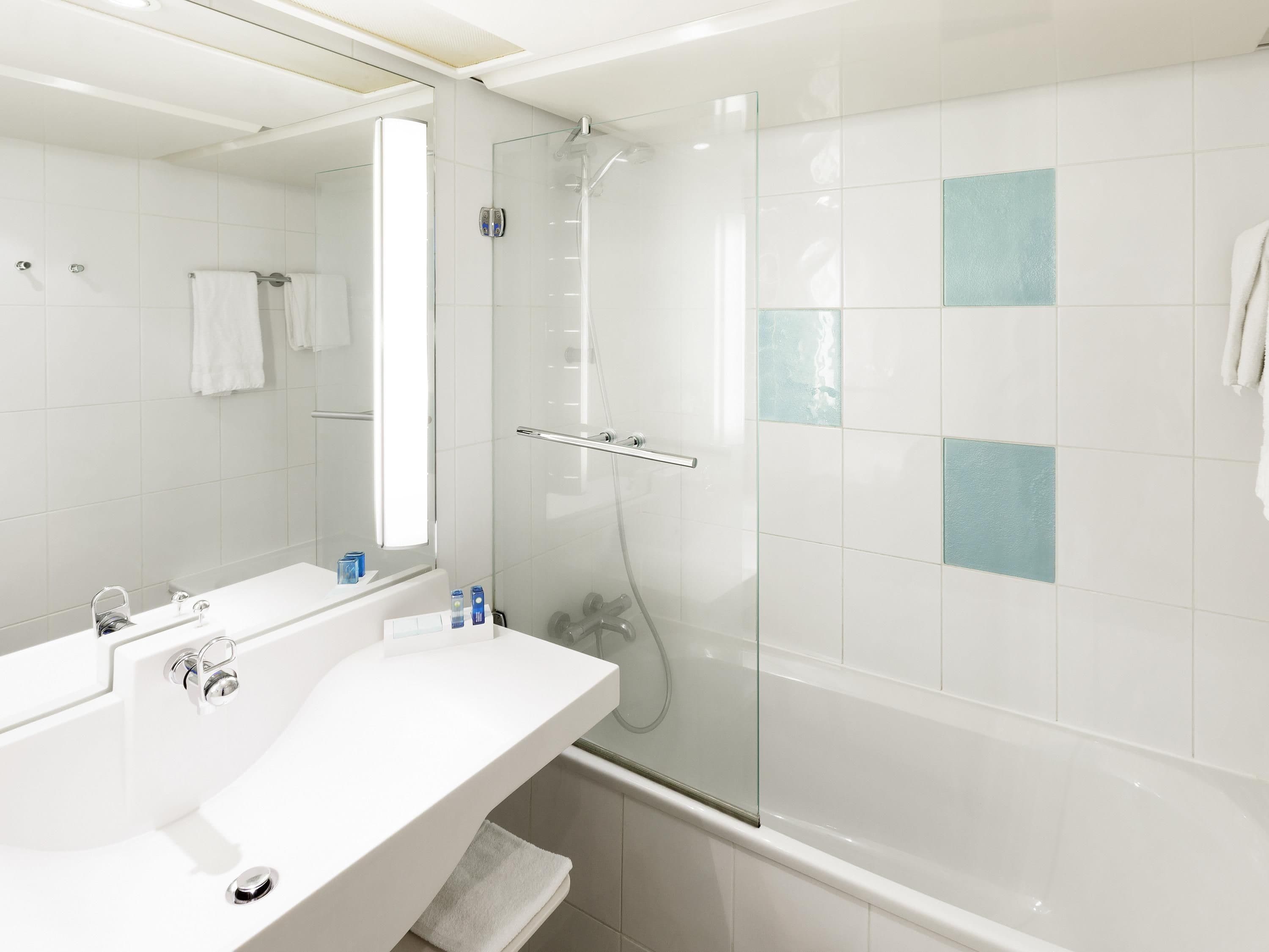 A modern bathroom with a glass-enclosed shower, a white sink with a mirror, and a bathtub.