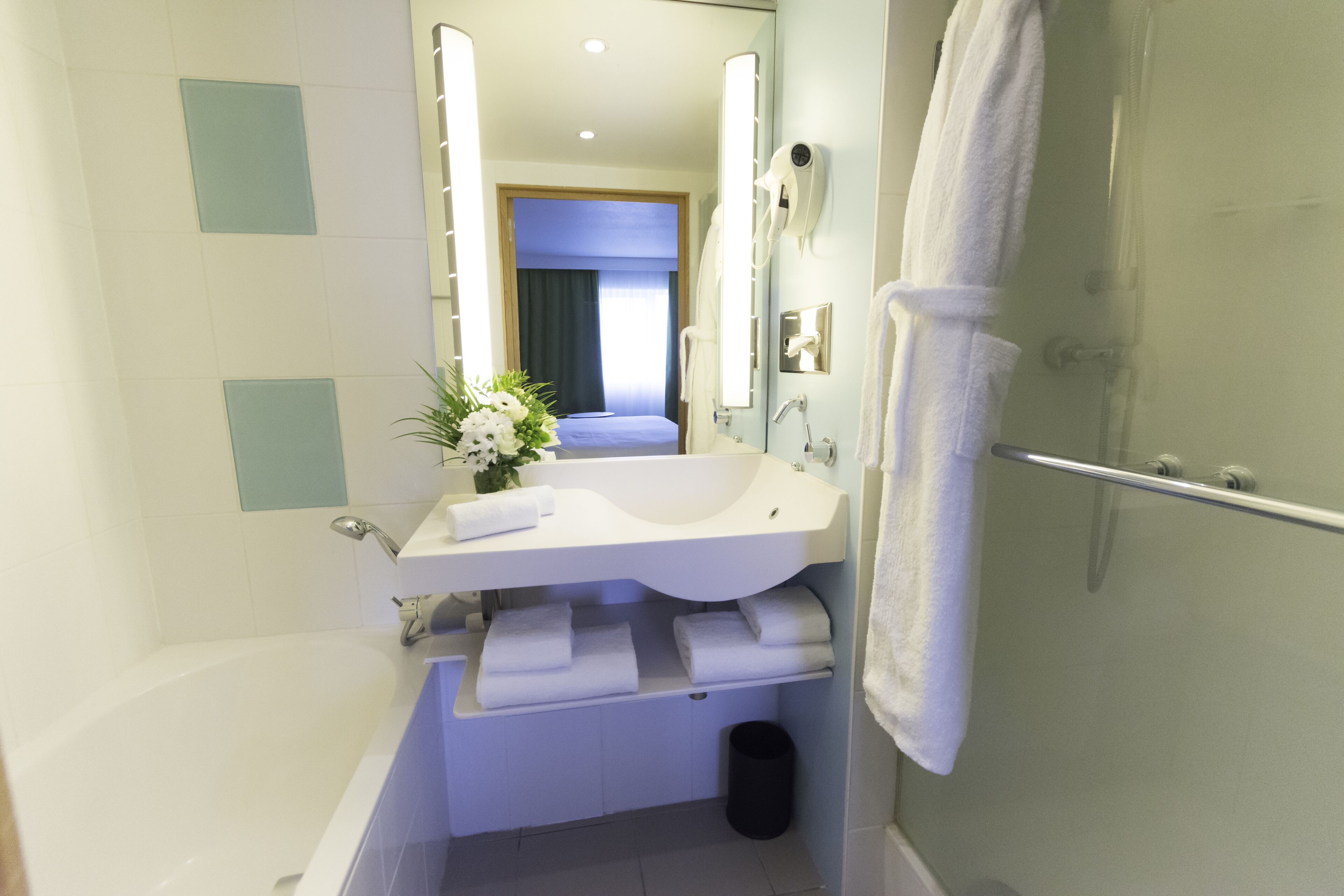 A modern bathroom with a bathtub, a sink with a mirror, and a shower.