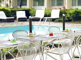 Una piscina al aire libre, sombrillas, sillones reclinables de piscina